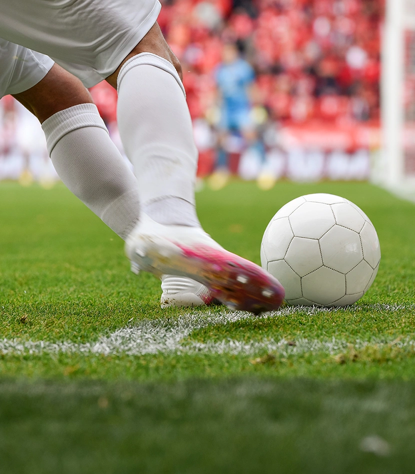 image of soccer player kicking ball on turf